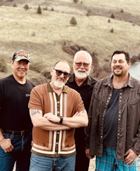 a group of men posing for a picture in front of a mountain